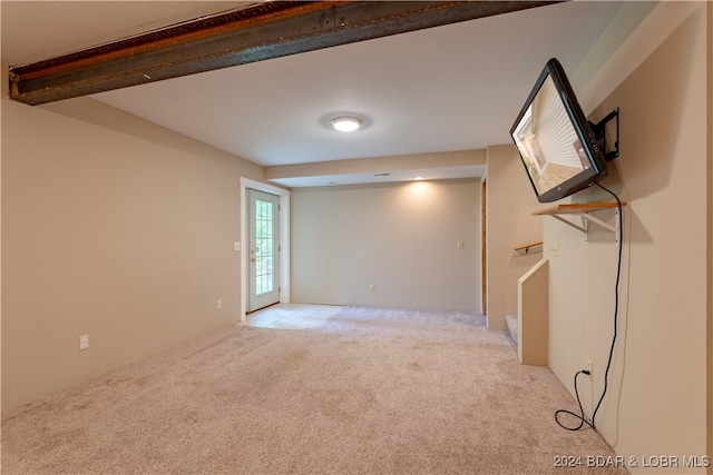 carpeted empty room featuring beamed ceiling