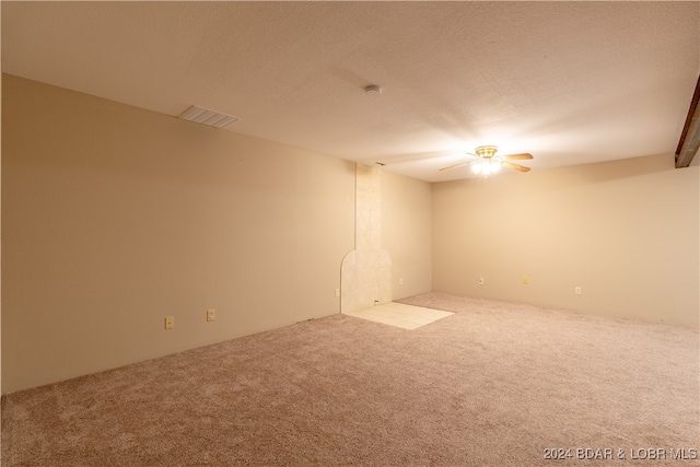 empty room featuring a textured ceiling, ceiling fan, and light carpet