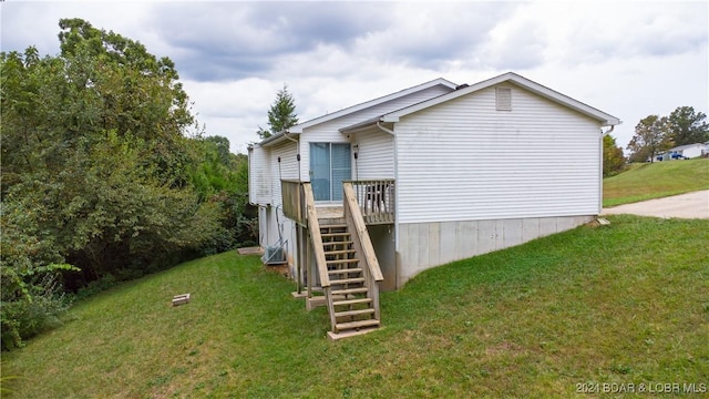 view of side of home with a deck and a lawn