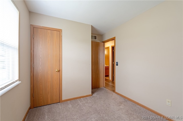 unfurnished bedroom with light carpet and a closet