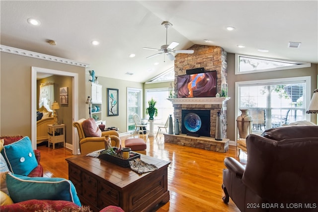 living room featuring ceiling fan, a stone fireplace, vaulted ceiling, and wood-type flooring