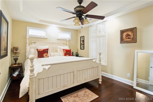 bedroom featuring ceiling fan, a raised ceiling, and dark wood-type flooring