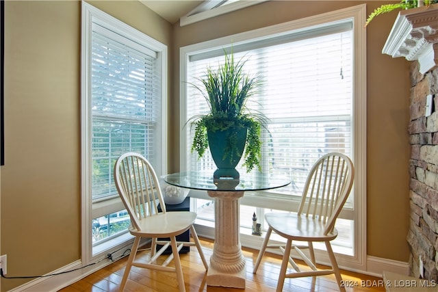 dining space with a wealth of natural light, vaulted ceiling, and hardwood / wood-style flooring