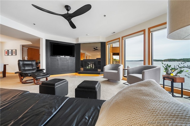 living room featuring a multi sided fireplace, ceiling fan, and carpet flooring