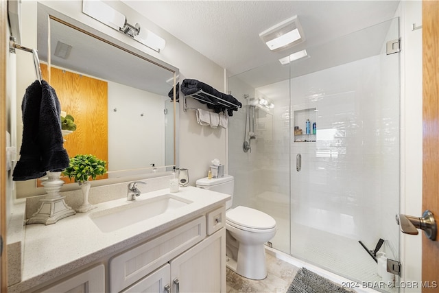 bathroom with vanity, a shower with shower door, toilet, and a textured ceiling