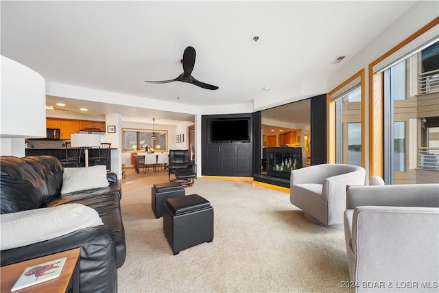 living room with ceiling fan, a fireplace, and light carpet