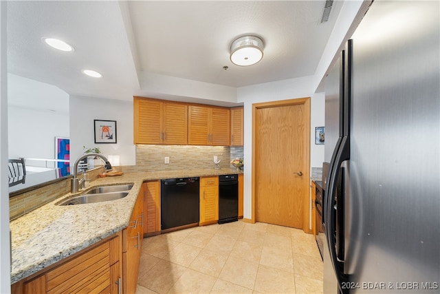 kitchen with black dishwasher, sink, backsplash, light stone countertops, and stainless steel fridge