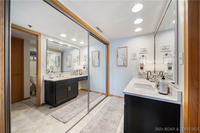 701 Cedar Rd Unit 1B, Lake Ozark, MO 65049 - full bath featuring visible vents, toilet, baseboards, two vanities, and a sink
