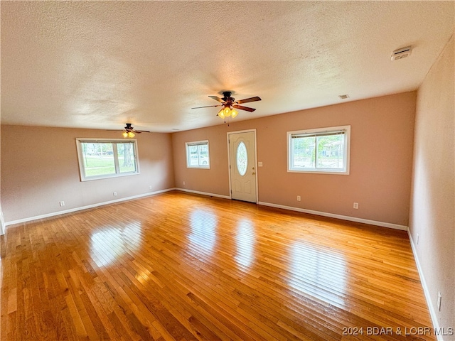 unfurnished room with ceiling fan, a textured ceiling, and light hardwood / wood-style flooring