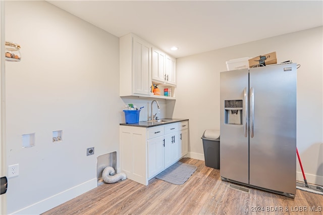 kitchen with stainless steel refrigerator with ice dispenser, sink, light wood-type flooring, and white cabinetry