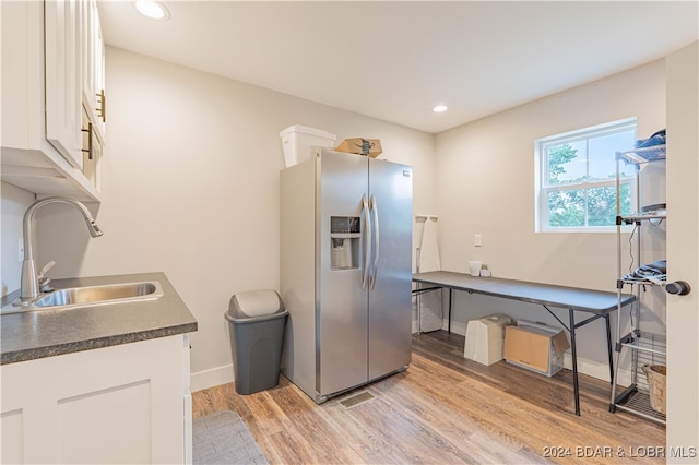 kitchen featuring stainless steel fridge, light hardwood / wood-style flooring, sink, and white cabinets