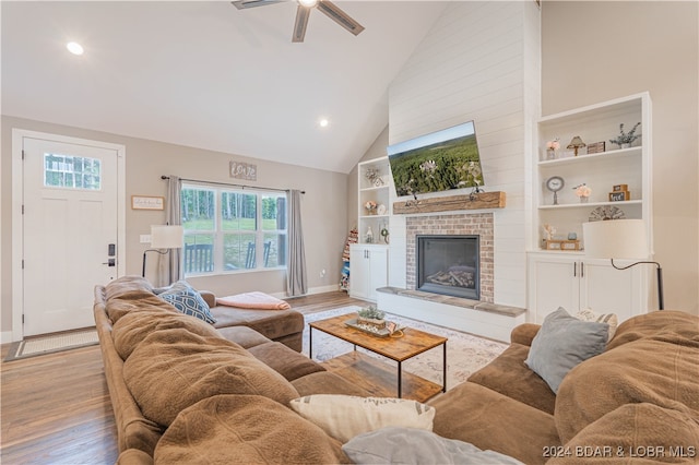 living room featuring ceiling fan, a fireplace, light hardwood / wood-style floors, and high vaulted ceiling