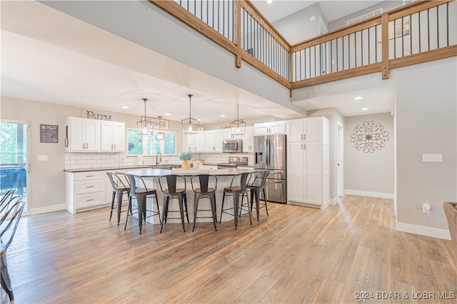 kitchen featuring light hardwood / wood-style flooring, stainless steel appliances, white cabinetry, and a kitchen island