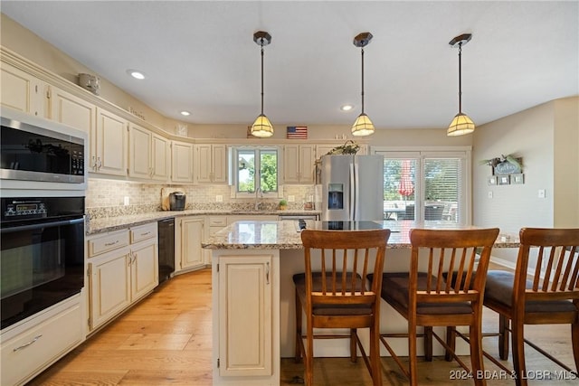kitchen with stainless steel appliances, a center island, a sink, light wood-type flooring, and backsplash