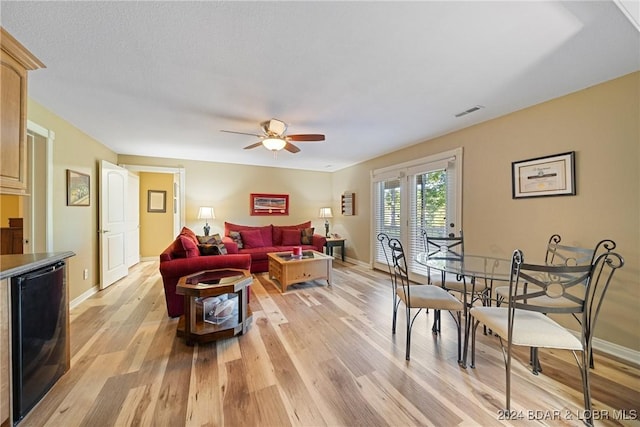 living room with ceiling fan, baseboards, light wood-style floors, and visible vents