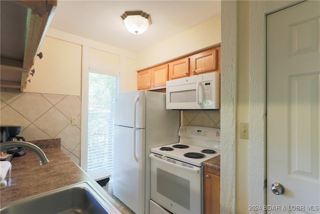 kitchen with backsplash, white appliances, and sink