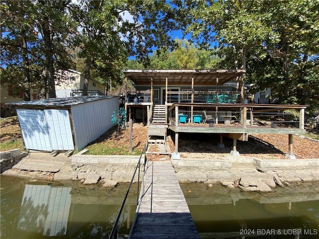 back of house with a storage unit and a water view