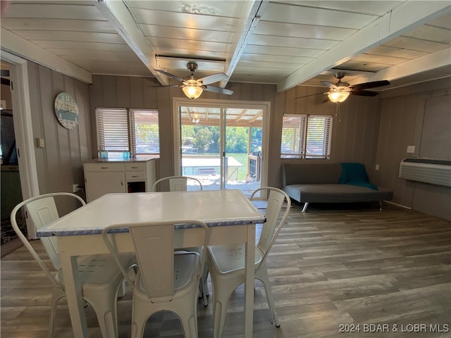 dining space featuring ceiling fan, wooden walls, and hardwood / wood-style floors