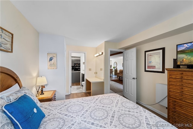 bedroom featuring wood-type flooring and ensuite bath