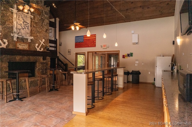 interior space featuring a stone fireplace, a towering ceiling, ceiling fan, and hardwood / wood-style flooring