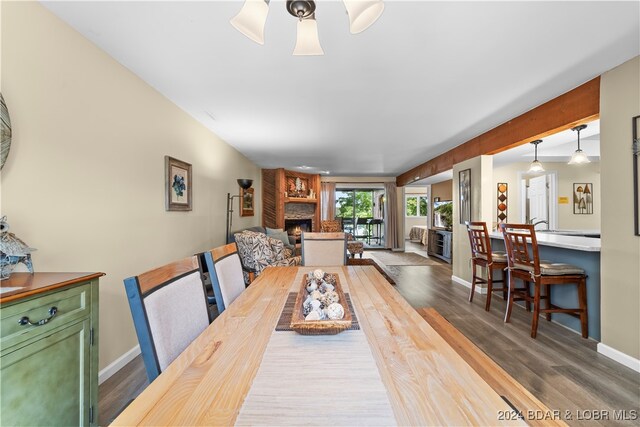 dining room featuring a fireplace, hardwood / wood-style floors, and ceiling fan