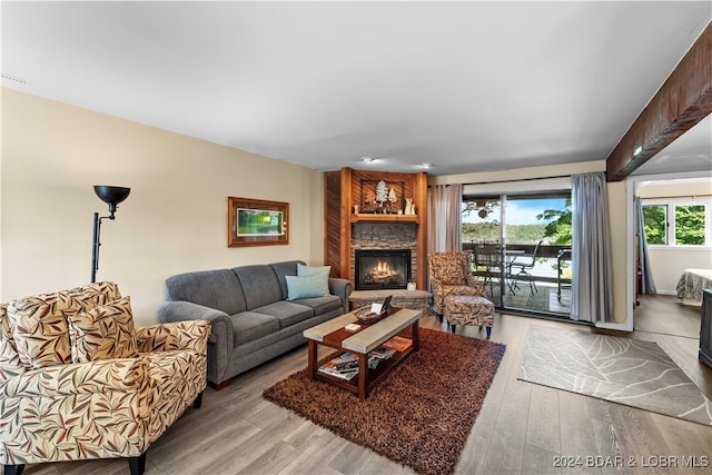 living room with light hardwood / wood-style floors, a fireplace, and beam ceiling