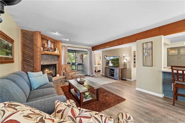 living room featuring a stone fireplace and light hardwood / wood-style flooring