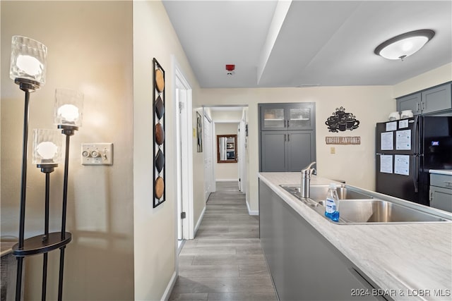 kitchen with pendant lighting, hardwood / wood-style flooring, sink, and black refrigerator