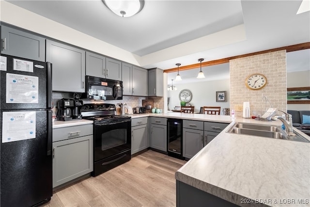 kitchen with black appliances, kitchen peninsula, sink, and pendant lighting