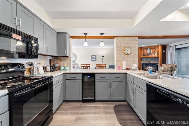 kitchen with kitchen peninsula, pendant lighting, black appliances, beverage cooler, and sink