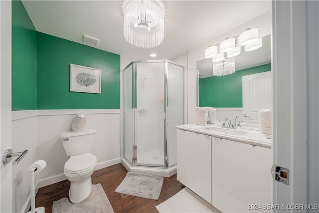 bathroom featuring wood-type flooring, a shower with door, toilet, and vanity