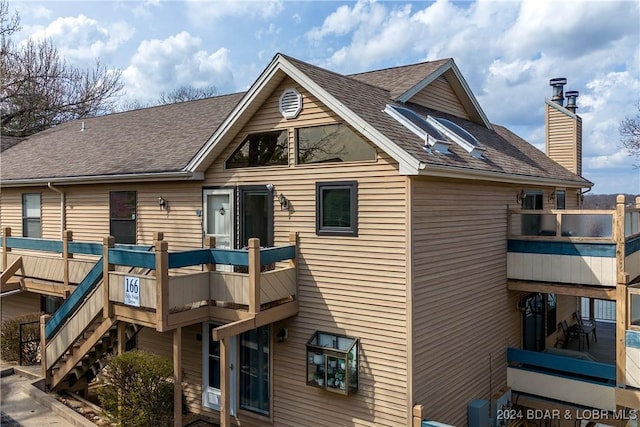 166 Falls Point Dr Unit 2B, Lake Ozark, MO 65049 - back of property featuring a shingled roof, a chimney, and a balcony