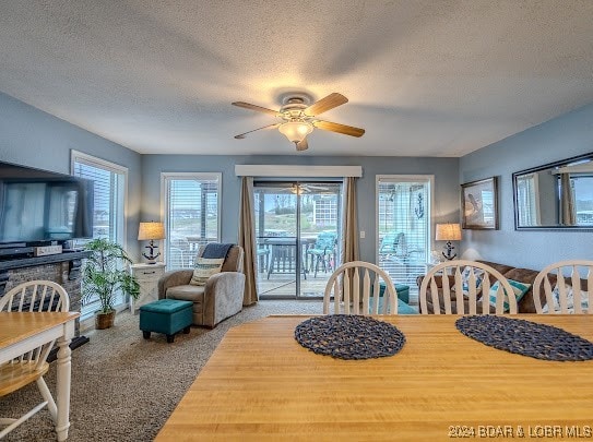 carpeted dining area featuring a textured ceiling, ceiling fan, and plenty of natural light