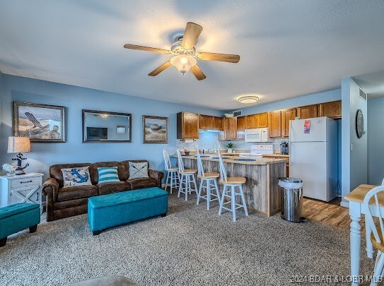 carpeted living room with ceiling fan