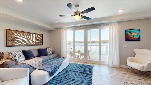 living room featuring light hardwood / wood-style flooring, a water view, and ceiling fan