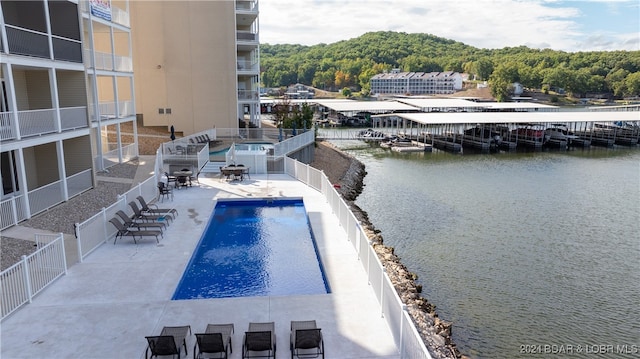 view of swimming pool with a water view and a patio area