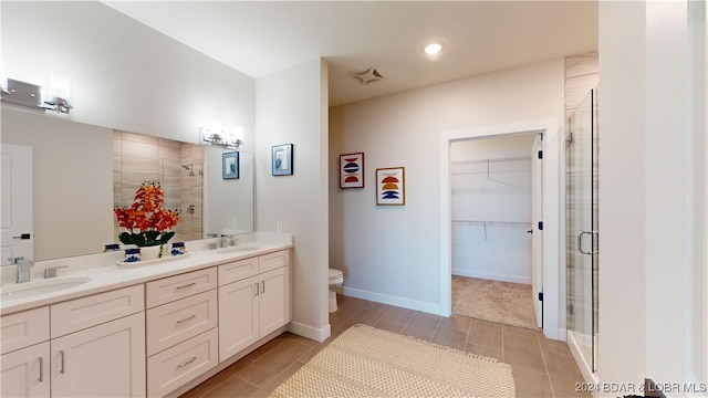 bathroom with a shower with door, toilet, vanity, and tile patterned floors