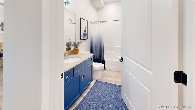 full bathroom with wood-type flooring, shower / bath combination with curtain, vanity, and toilet