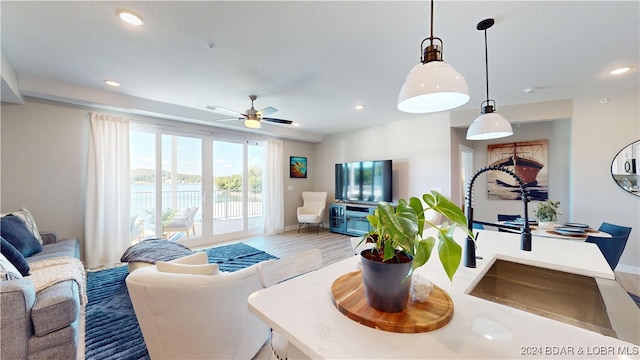 living room with light hardwood / wood-style floors, sink, and ceiling fan