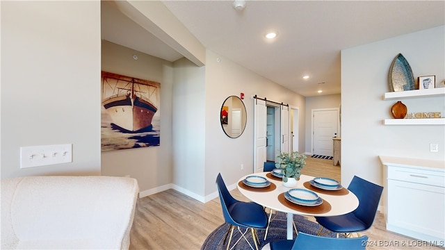 dining area featuring light wood-type flooring and a barn door