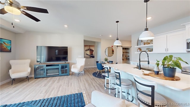 kitchen featuring light hardwood / wood-style floors, a breakfast bar, white cabinets, decorative light fixtures, and sink