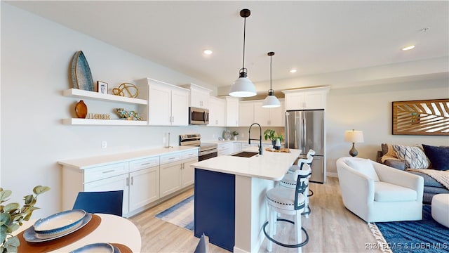 kitchen featuring white cabinets, appliances with stainless steel finishes, decorative light fixtures, and sink