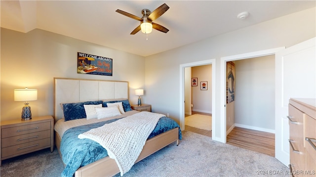 bedroom with light carpet, ensuite bath, and ceiling fan