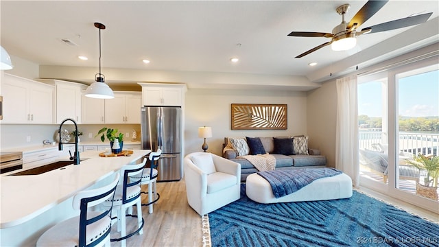 living room with light hardwood / wood-style floors, ceiling fan, and sink