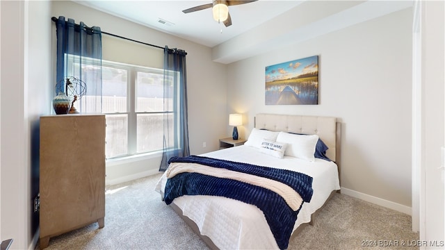 bedroom featuring ceiling fan, light carpet, and multiple windows