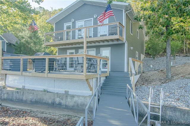 rear view of property featuring a balcony and a deck