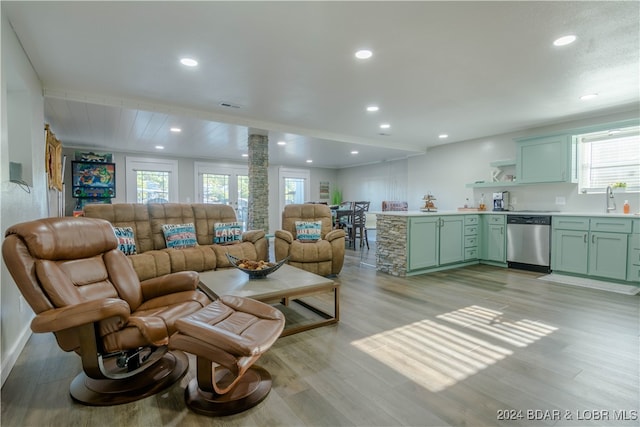 living room featuring sink, light wood-type flooring, plenty of natural light, and ornate columns