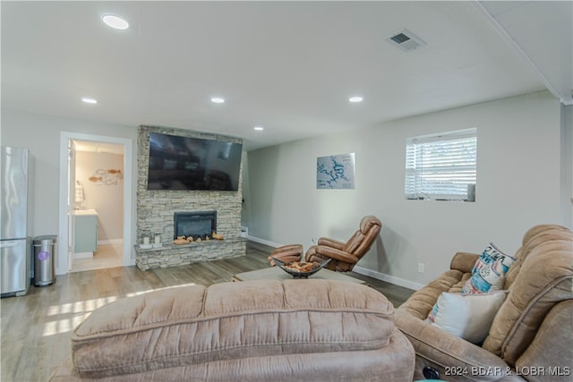 living room featuring a stone fireplace and light hardwood / wood-style floors