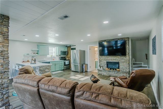 living room with a stone fireplace, light hardwood / wood-style floors, and sink