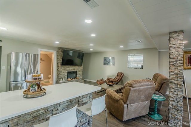 living room featuring light wood-type flooring, a fireplace, and ornate columns